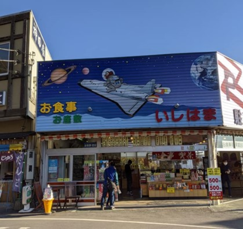カエルがロケットに乗って宇宙を目指している絵が描かれたお食事処の看板。