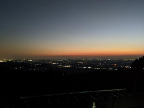 日没寸前の夕焼けと眼下に広がる夜景を頂上から撮影している。