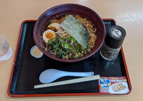 テーブルの上のお盆にラーメンがのせられている。ラーメンには煮卵、海苔、たっぷりのにんにくがトッピングされている。