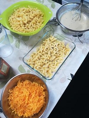 器に入ったゆでたマカロニとソース、チェダーチーズがテーブルに置かれている