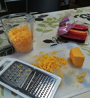 チーズおろし器で、チェダーチーズをおろしている