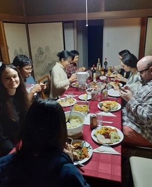 8人でテーブルを囲み、感謝祭の料理を食べている