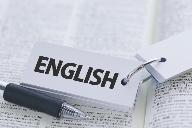 英語の辞書の上にENGLISHと書かれた単語帳とペンが置かれている