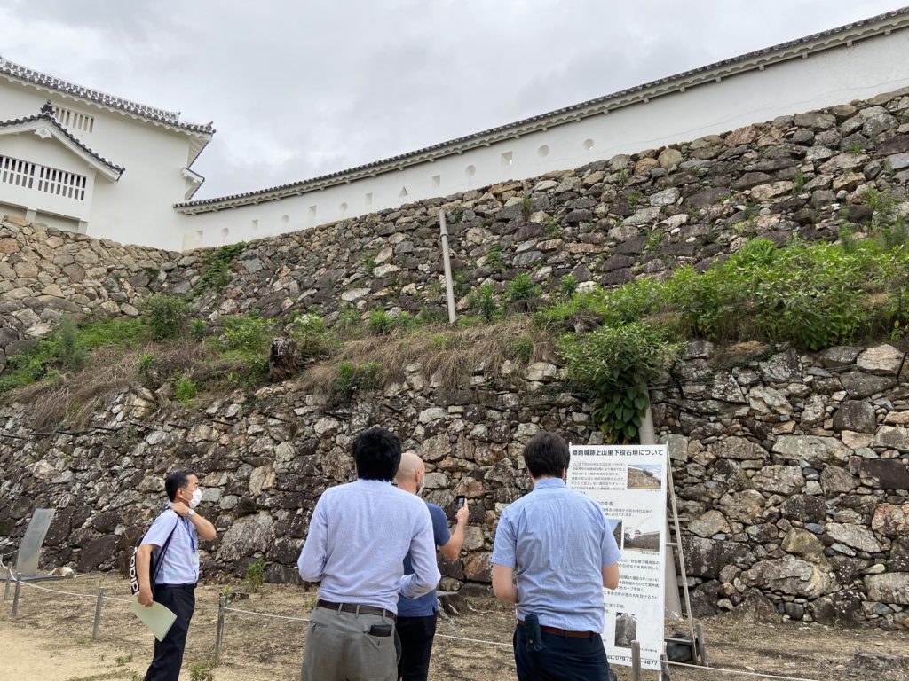 姫路城にある石垣の前に4人の男性が立っていて、石垣の説明を受けている写真です。