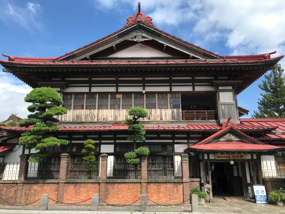 青森県金木町（現在の五所川原市）にある太宰治の実家です。外見は和風建築で、赤い屋根瓦が印象的です。