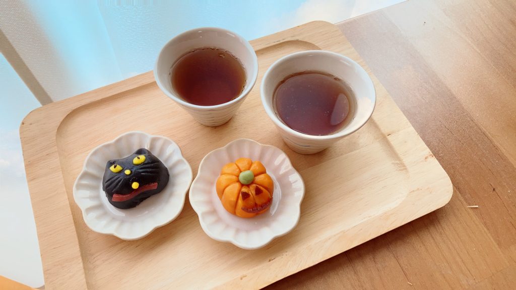 黒猫とパンプキンの形をしたハロウィンの主菓子と、日本茶がセットになった写真です。
