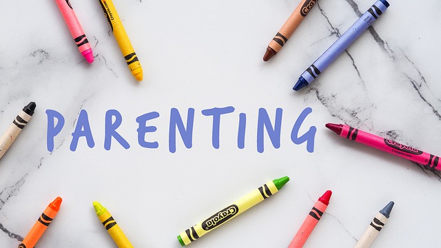 大理石の背景にparenting(育児)というテキストが記載してあり、周囲にクレヨンが散らばっています。